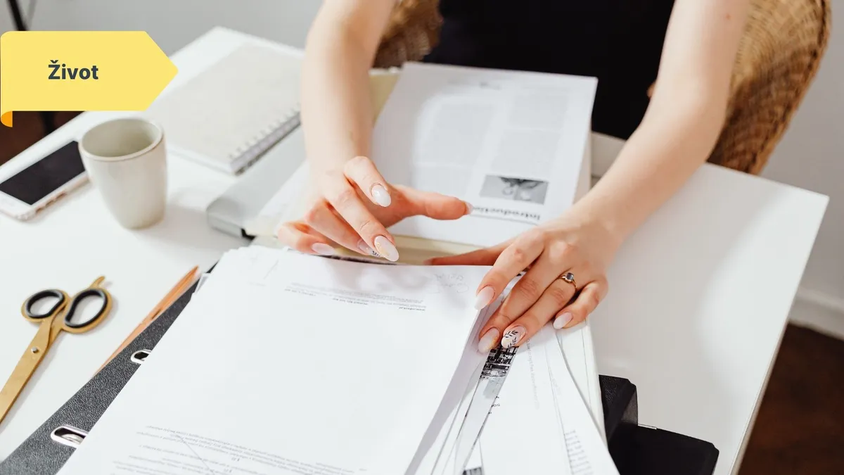 Žena organizuje papíry a smlouvy na psacím stole do šanonu.